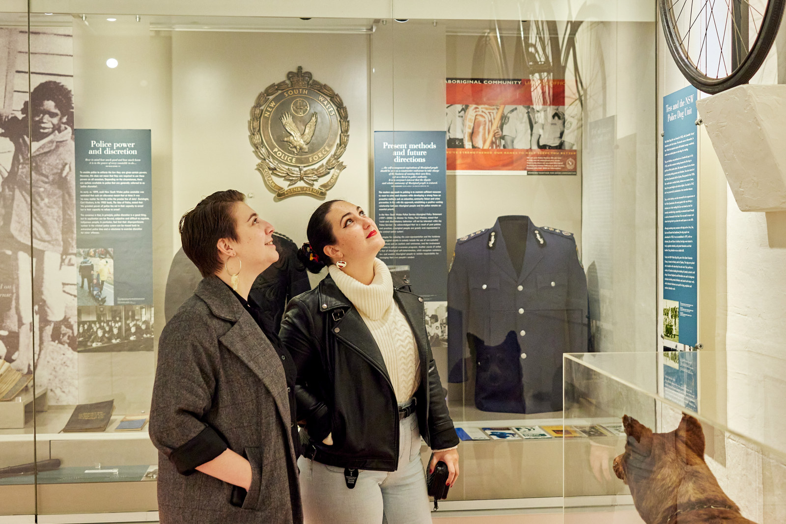 Two visitors look at the interpretation panels and objects within the cells of the museum.