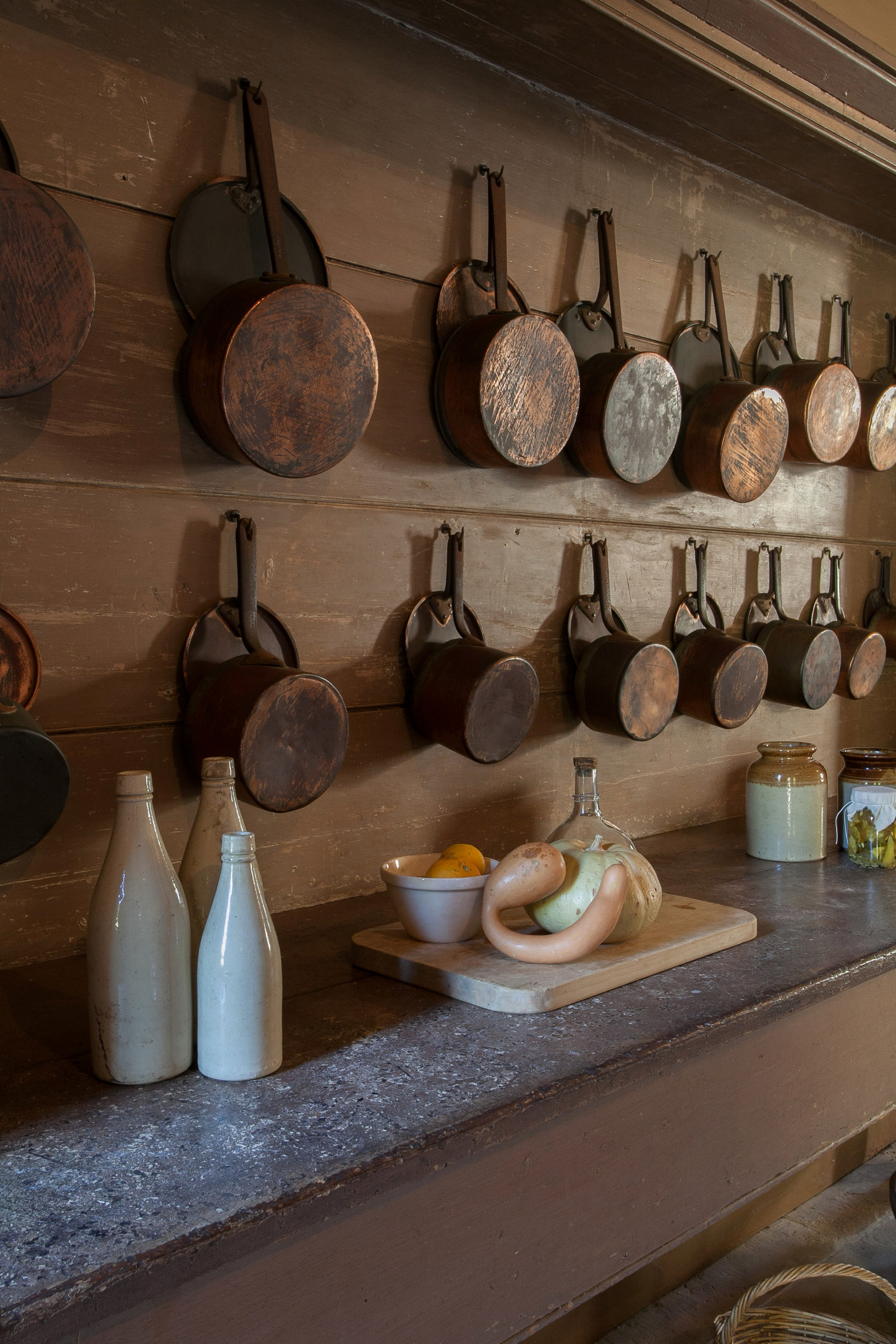 Clay bottles, a gourd, a bowl of oranges, a pumpkin and pots hanging on the brown painted cedar dresser in kitchen, Vaucluse House
