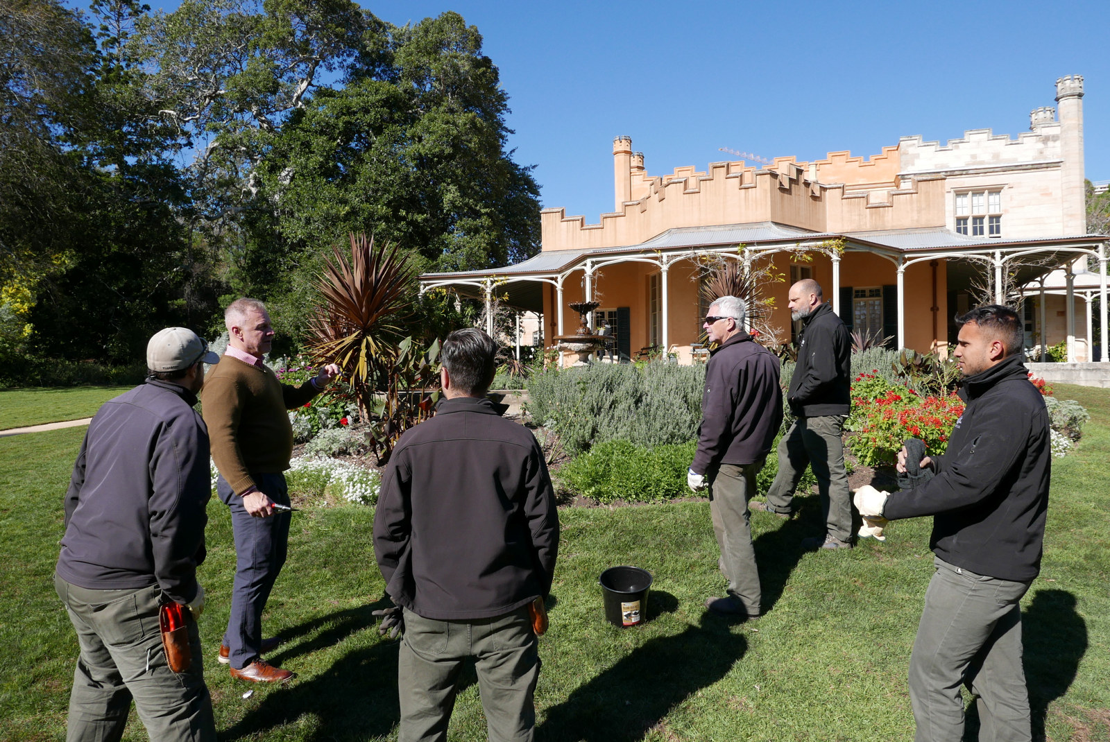 Ian Innes and the horticulture team discussing rose pruning techniques in front of Vaucluse Hosue