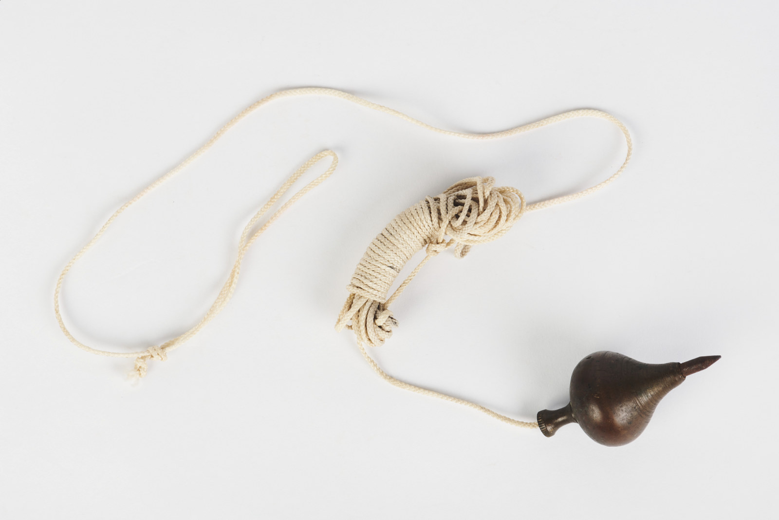Dark and heavy metal plumb-bob with attached plaited synthetic cord, used by Max Fry during refurbishments of the Hyde Park Barracks, circa 1950s