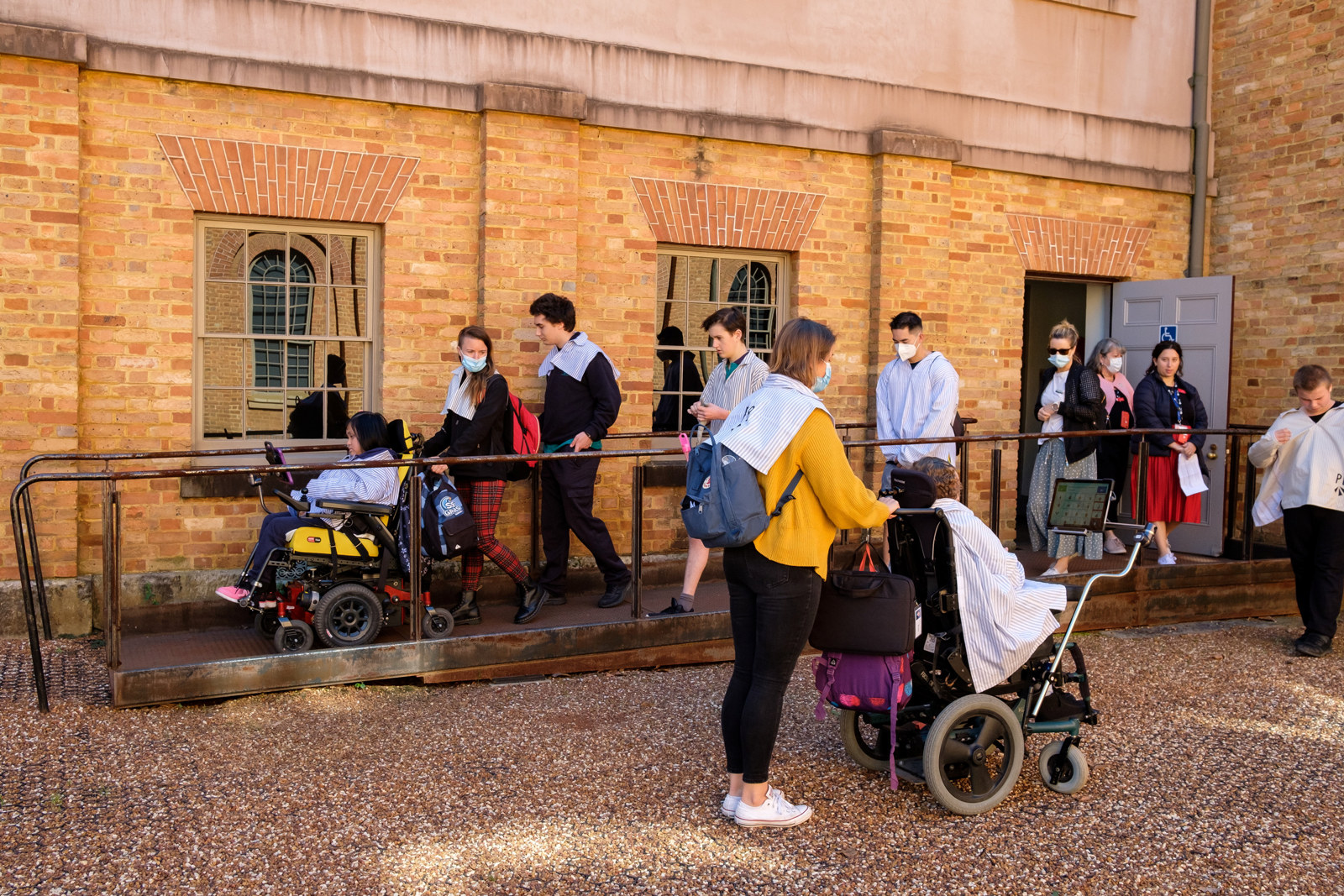 Line of students and carers, some students in wheelchairs, going down the ramp outside Hyde Park Barracks.