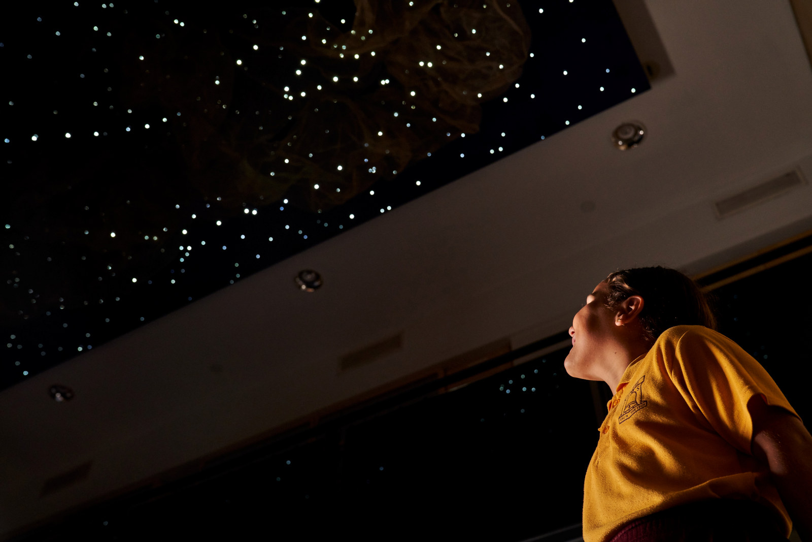 A student  gazing up at the night sky light sculpture as part of the Garuwanga Gurad (Stories that belong to Country) program at the Museum of Sydney