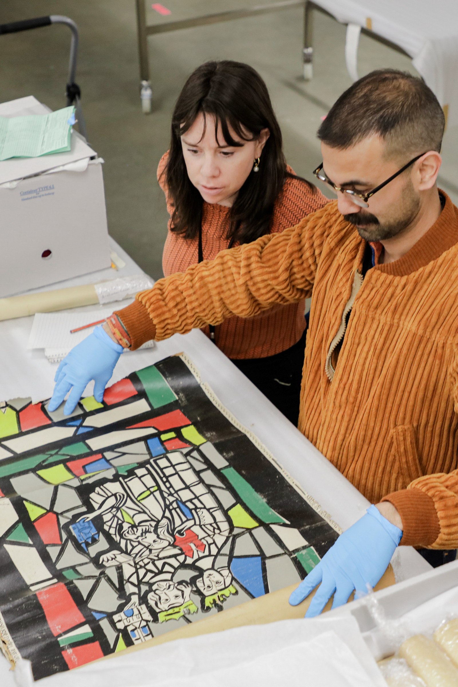 Alex Shapley and Aaron de Souza view a wallpaper sample book from the John and Phyllis Murphy collection, Museums Discovery Centre