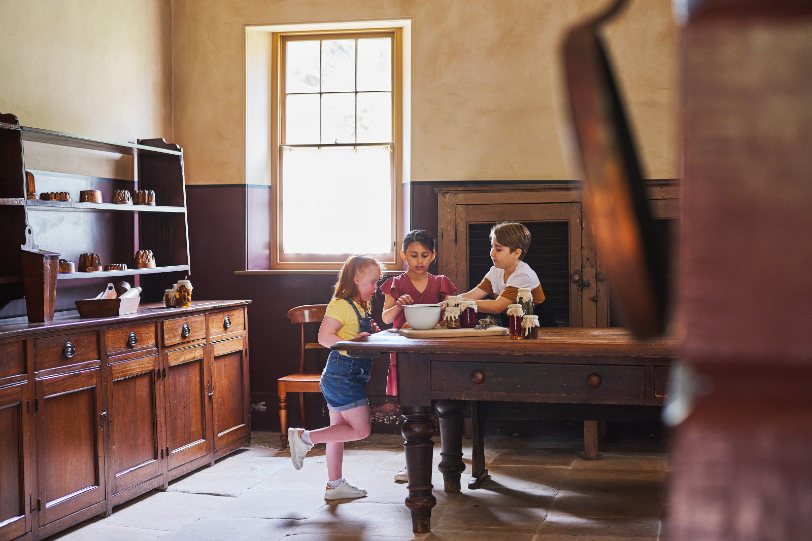 A group of children looking at objects on a table in Vaucluse House Kitchen